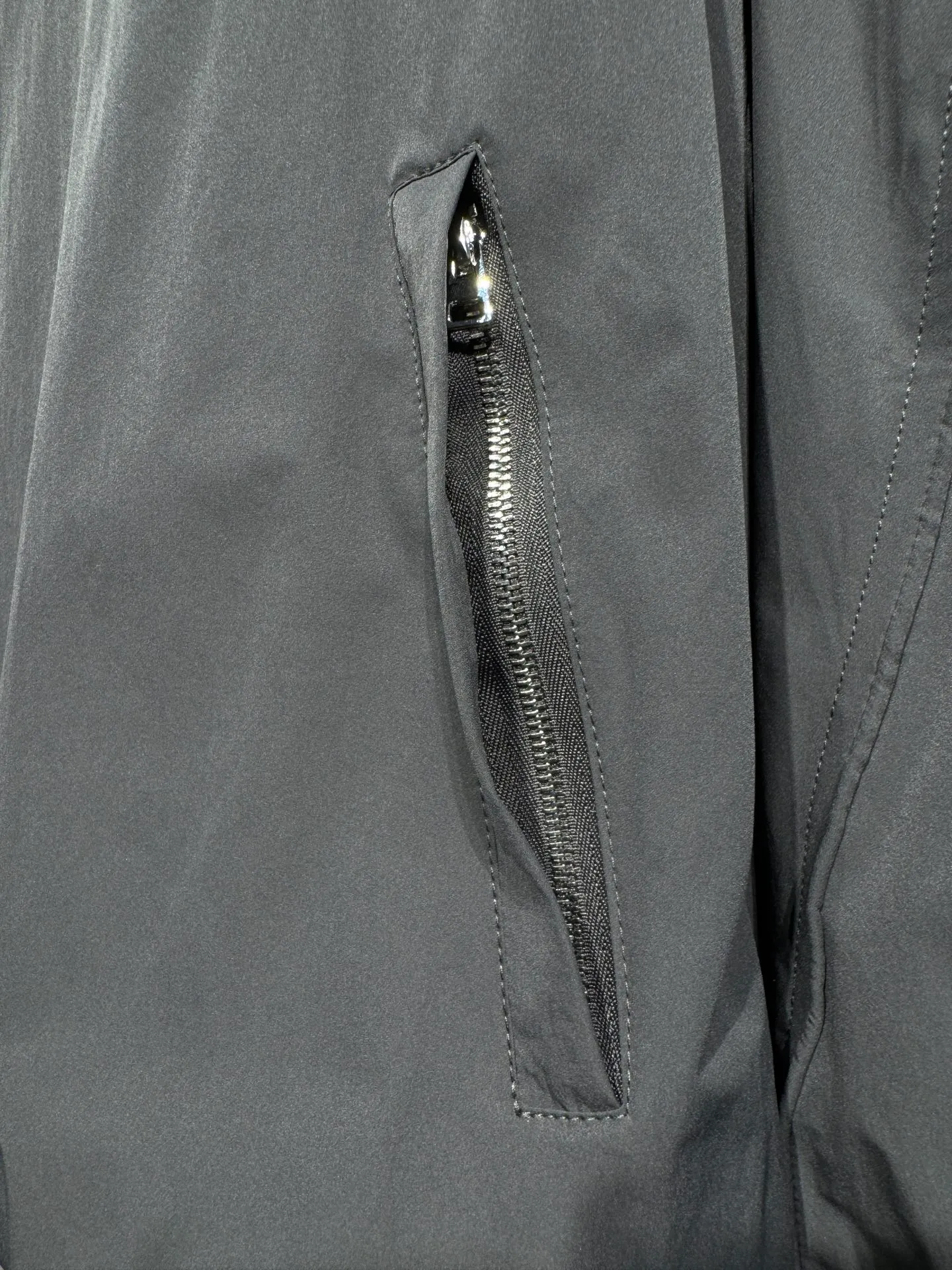 Acne Studios 26SS Large Lapel Short Jacket The fabric is made of 100% nylon (nylon/polyamide fiber) 75D high-density wrinkled nylon. The fabric has been permanently pressed and shaped by high temperature, and washed with high-pressure wrinkles at the factory to form its own irregular texture, permanently retaining the wrinkled texture, which will not disappear after washing. Matte matte coating removes the plastic glossy surface of nylon itself to create a low-key matte paper feel. Three-proof micro-coating, weak waterproof, anti-fouling, anti-static treatment, not easy to get dust. The interior is made of full-width mesh Breathable nylon lining, which reduces the stickiness of the nylon fabric to the body, improves air circulation, prevents sweating from sticking to the skin, and the zipper does not rub against the skin. The version adopts the raglan split topstitching process, and the front and rear panels are divided diagonally to expose even stitching. The three-dimensional dropped shoulders are loose and the fit is increased to increase the margin of movement. The back neckline is three-dimensional and high-density computer embroidered, and the embroidery lines are dense and not prickly. Customized all-metal matte nylon zipper, Genuine Leather embossed brand letters on the zipper leather tab, zipper tape with same color nylon fit to the body, double-locked reinforcement on both sides of the zipper to prevent pulling and tearing. Color: Gray Size: S M L